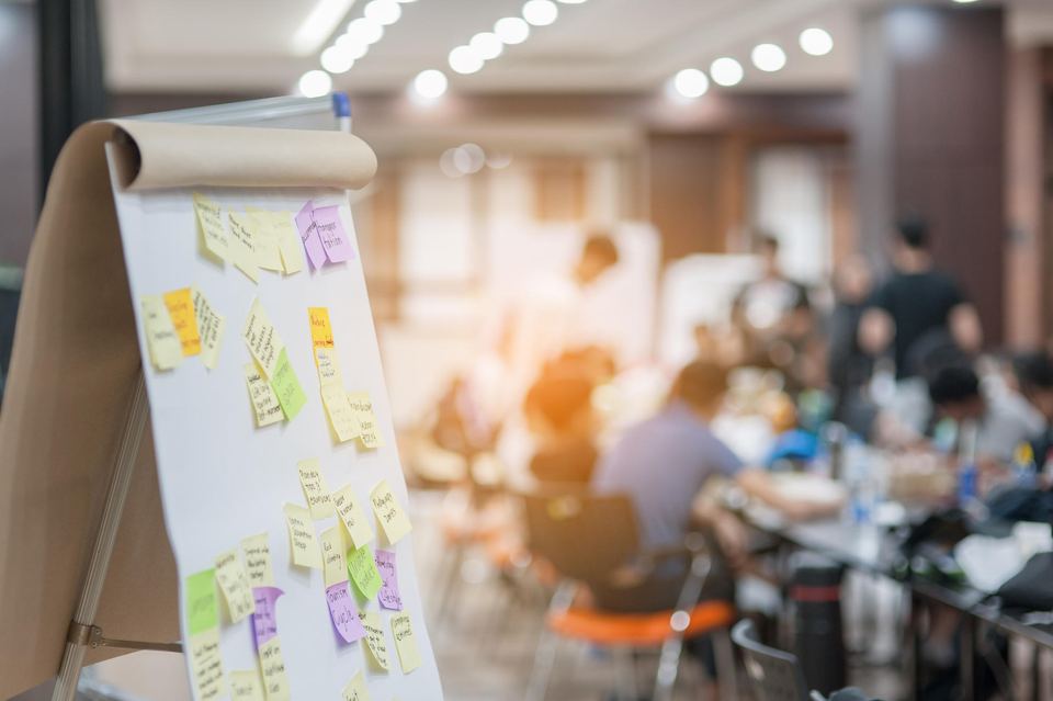 Workshop participants collaborating around a flip chart covered with sticky notes